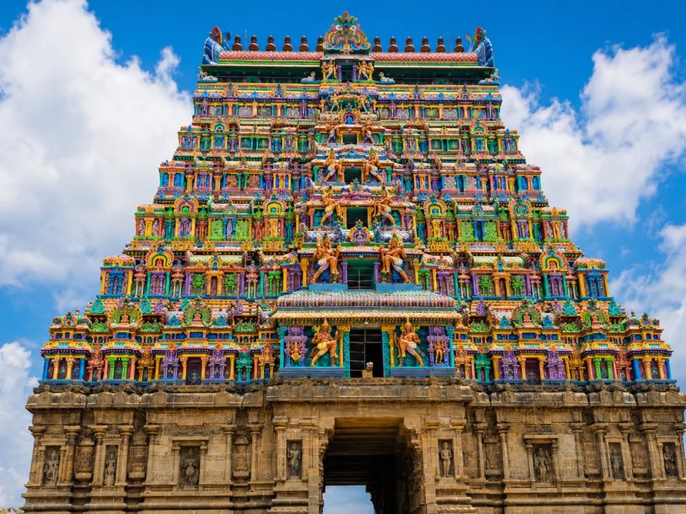 A brightly painted temple gopuram rising above its stone gateway in Tamil Nadu